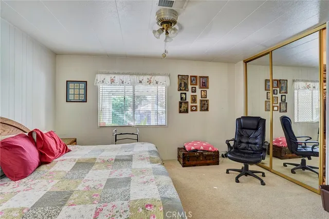 a bedroom with a bed a desk and chair with window