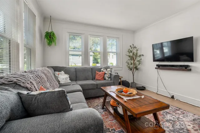 a living room with furniture a flat screen tv and a window
