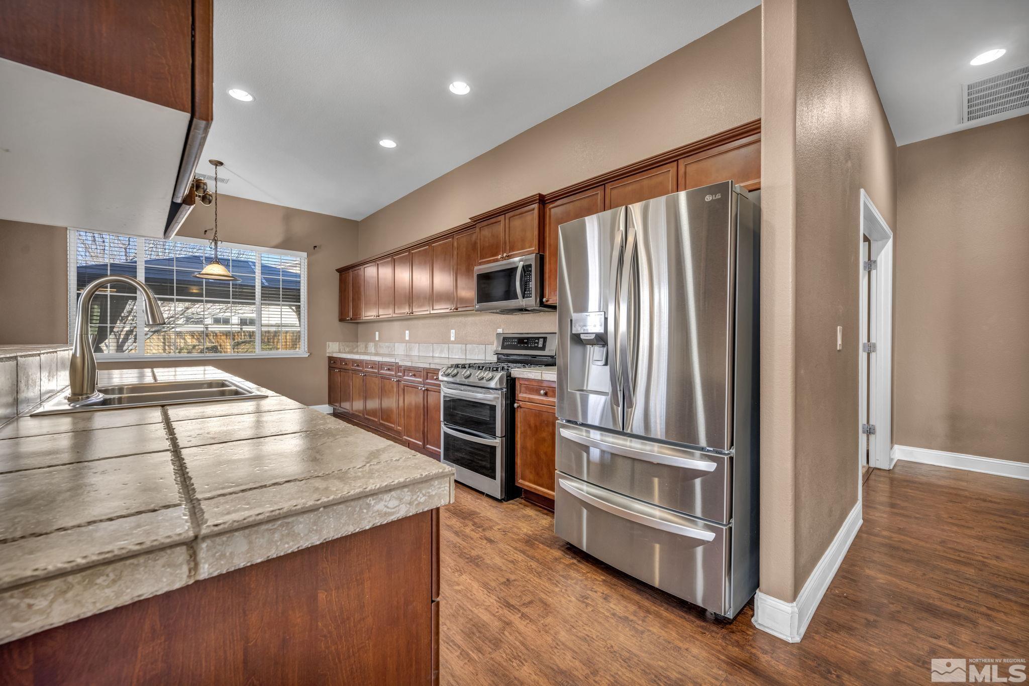 7301 Lacerta Drive Sparks, NV 89436 - Photo 22 of 39 a kitchen with stainless steel appliances granite countertop a refrigerator a stove and a sink with wooden floors