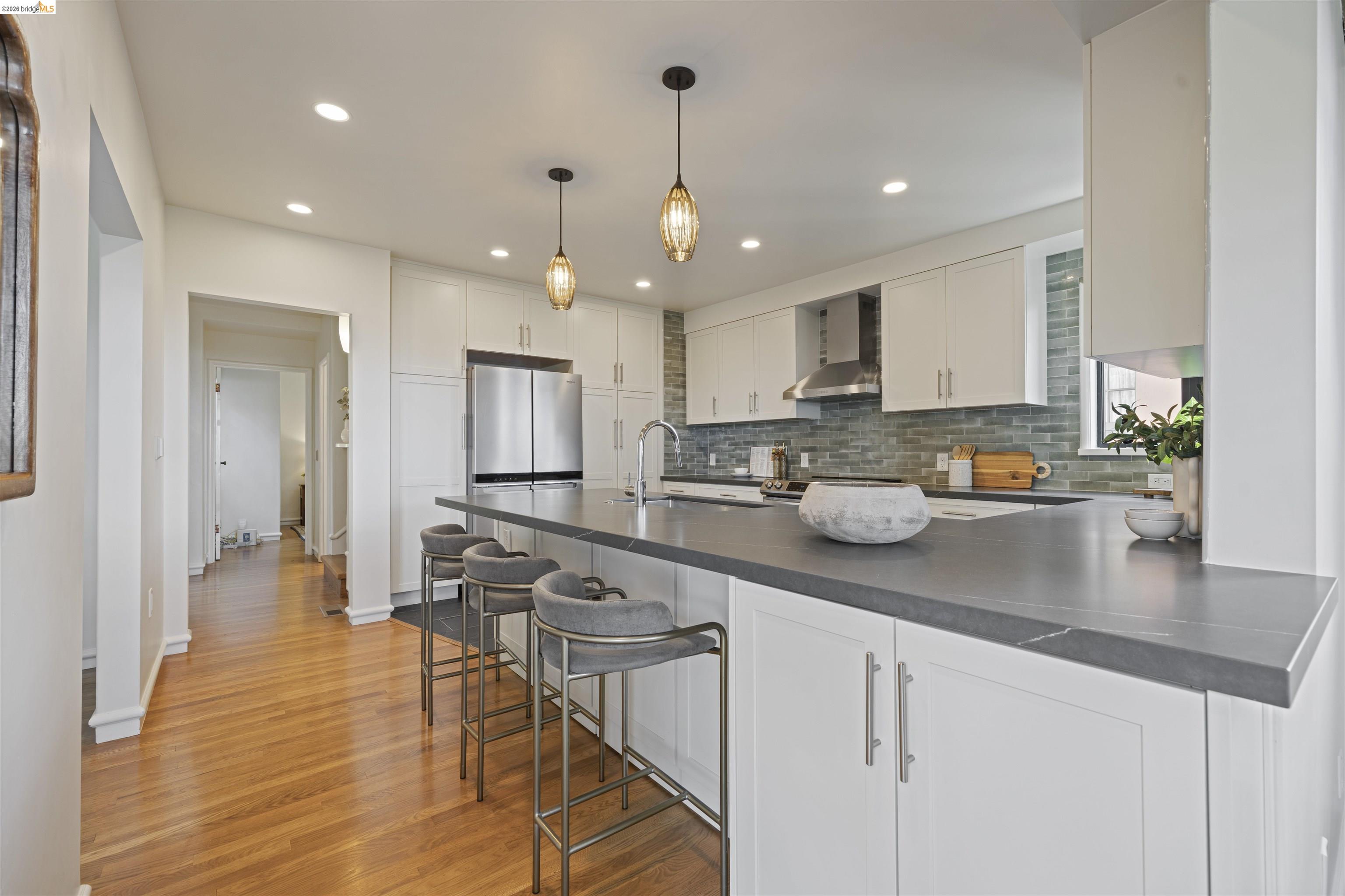 1170 Sterling Avenue Berkeley, CA 94708 - Photo 9 of 52 Kitchen with white cabinetry, a breakfast bar, dark countertops, light wood finished floors, and backsplash