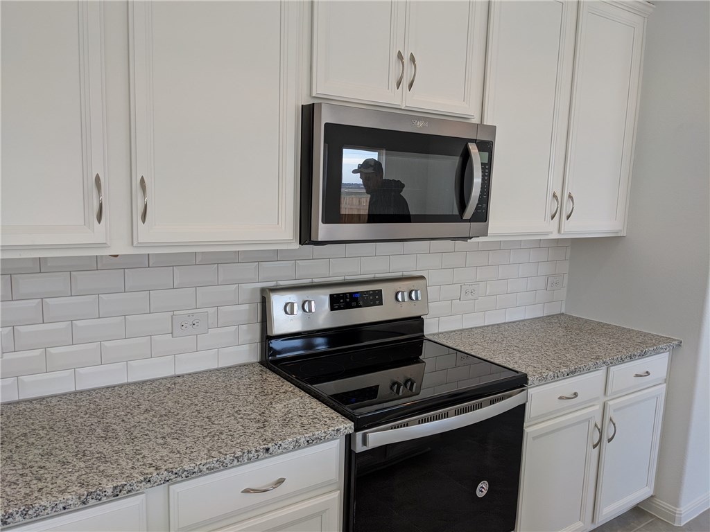 6705 Routenburn Street Austin, TX 78754 - Photo 5 of 18 a kitchen with granite countertop white cabinets appliances and a counter top