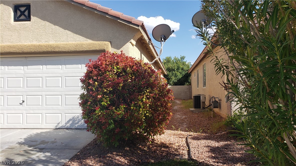 9112 Manalang Road Las Vegas, NV 89123 - Photo 5 of 50 A well-maintained side yard and garage, featuring a thriving green bush and gravel landscaping.