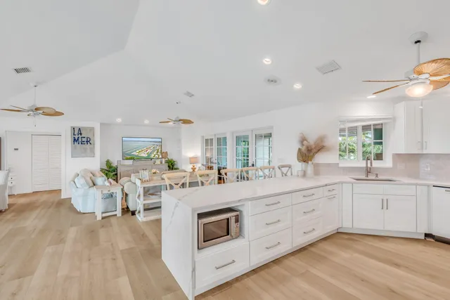 a large white kitchen with cabinets a sink and appliances