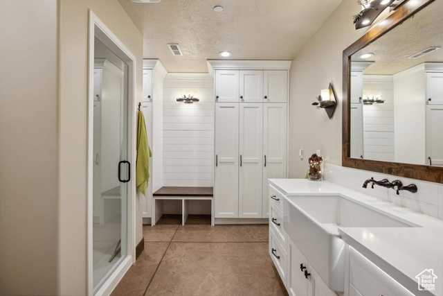 6117 North Rocky Ridge Road Peoa, UT 84061 - Photo 57 of 83 Bathroom featuring vanity, tile patterned flooring, a shower with door, and a textured ceiling