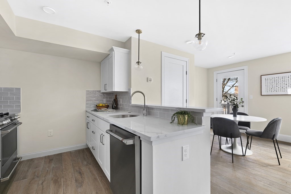 29 Ward Street, Unit 101 Boston, MA 02127 - Photo 6 of 11 a kitchen with stainless steel appliances granite countertop a stove a sink dishwasher and a refrigerator with wooden floor