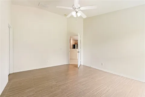 an empty room with wooden floor and ceiling fan