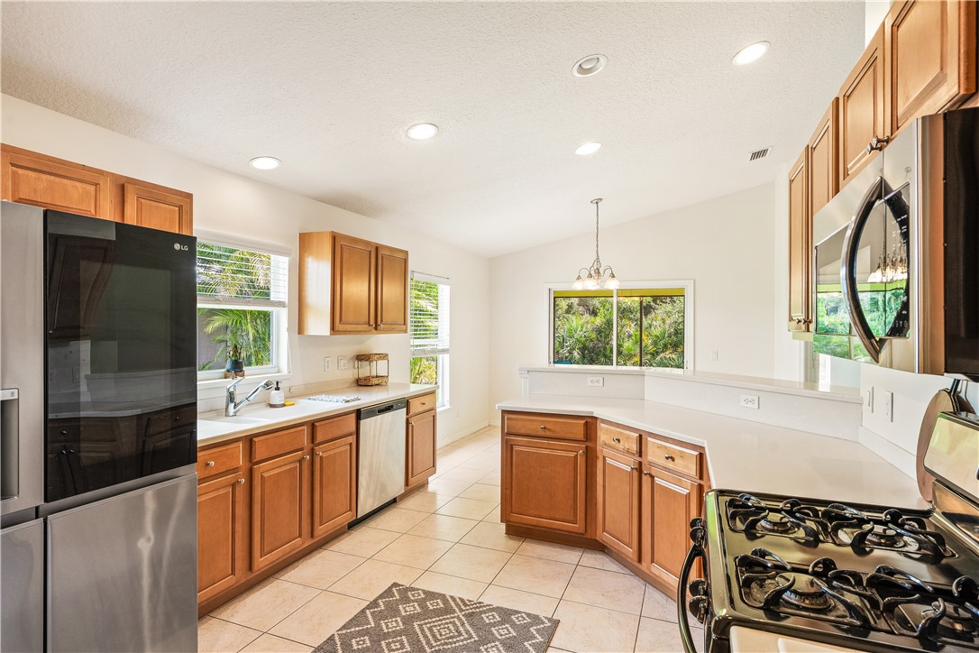 1087 4th Lane Southwest Vero Beach, FL 32962 - Photo 4 of 34 a large kitchen with stainless steel appliances a large counter top a stove a chimney a sink and a refrigerator