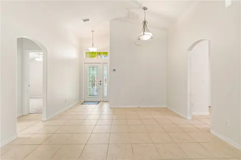 a view of an empty room with window and chandelier