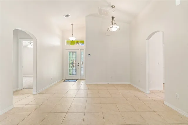 a view of an empty room with window and chandelier