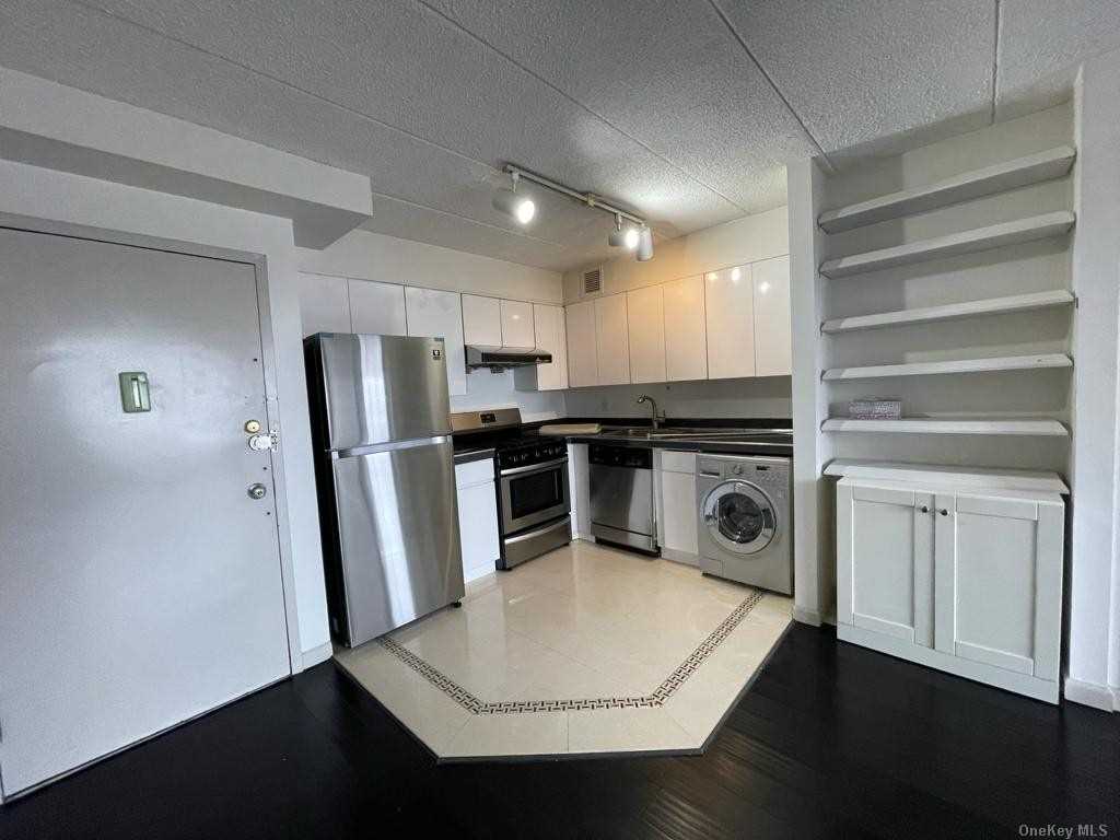 a kitchen with stainless steel appliances a refrigerator a stove and white cabinets