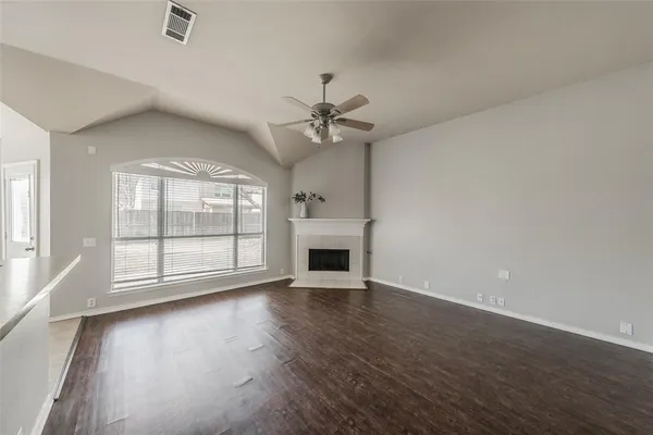 an empty room with wooden floor fireplace and windows