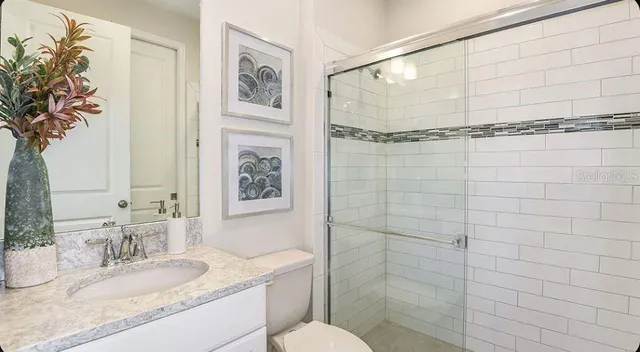 a bathroom with a granite countertop sink a toilet and shower