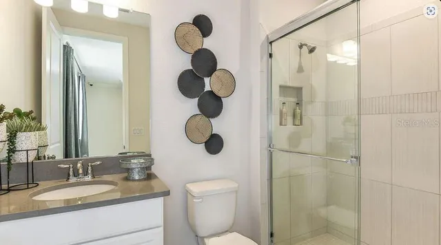 a bathroom with a granite countertop sink a toilet and shower