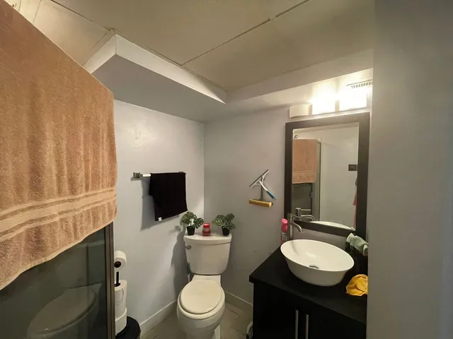 a bathroom with a toilet a sink a mirror and a window