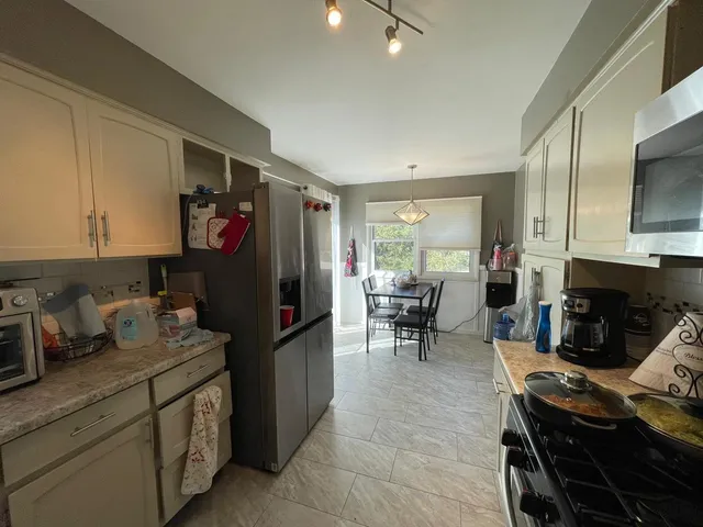 a kitchen with a refrigerator and a stove top open