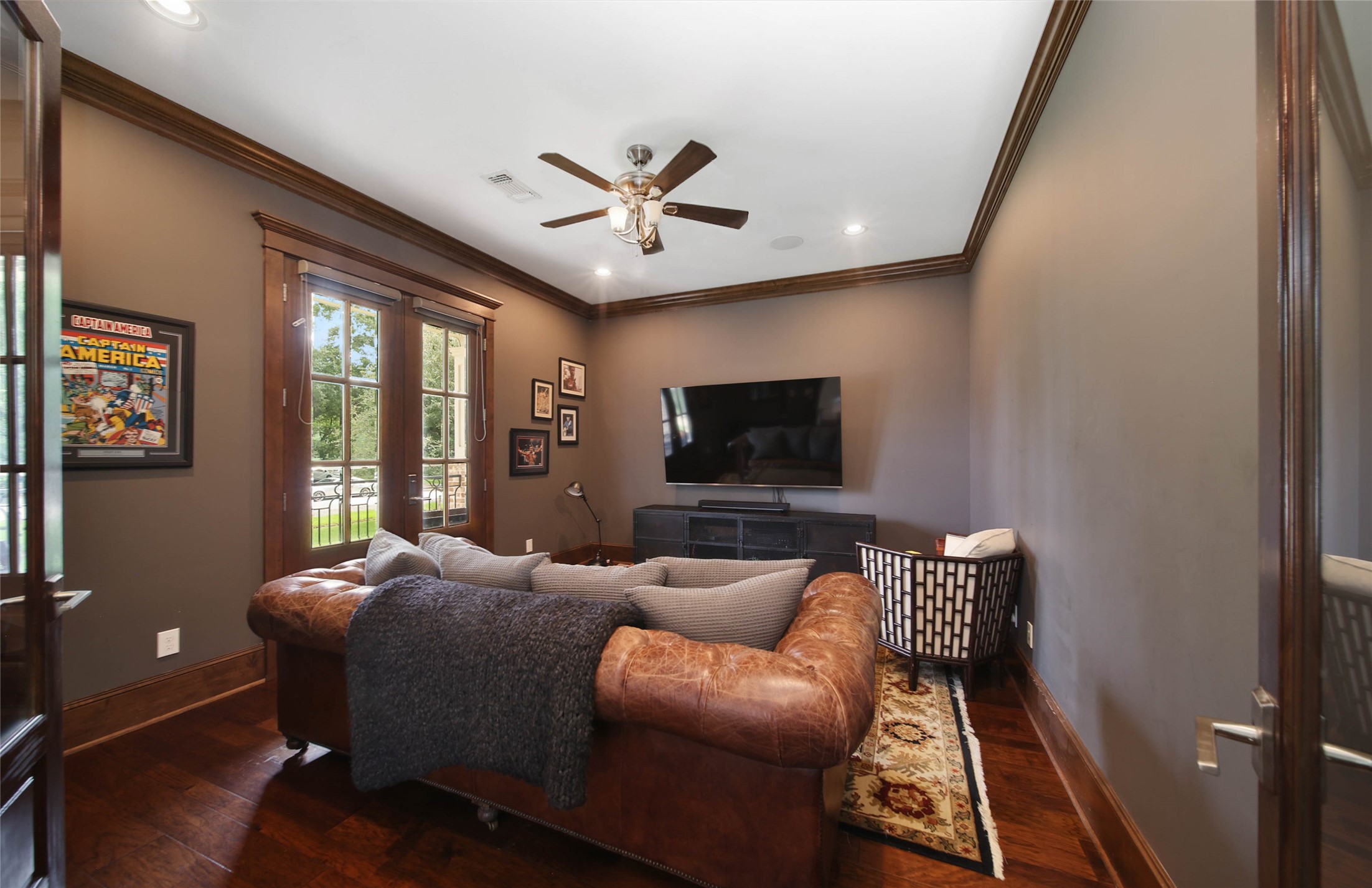 416 West 33rd Street Houston, TX 77018 - Photo 6 of 47 Sophisticated home office featuring rich dark wood crown molding, extra-high baseboards, gorgeous wood floors, and French doors opening to the front patio for abundant natural light. A warm and inviting workspace with timeless finishes and elegant architectural detail throughout.