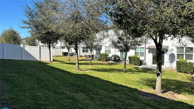 a view of a white house with a big yard and large tree