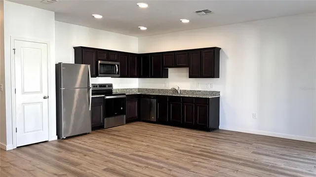 a kitchen with stainless steel appliances granite countertop a refrigerator and a sink