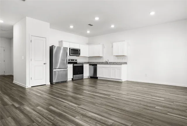 a kitchen with stainless steel appliances wooden floor and a refrigerator