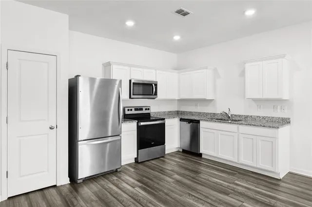a kitchen with a refrigerator cabinets and wooden floor