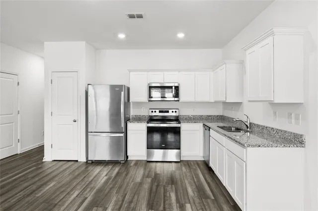 a kitchen with granite countertop white cabinets and stainless steel appliances