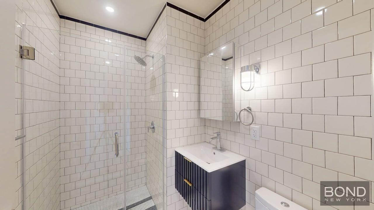 1031 Lorimer Street, Unit 2 Brooklyn, NY 11222 - Photo 10 of 15 a bathroom with a shower sink and mirror