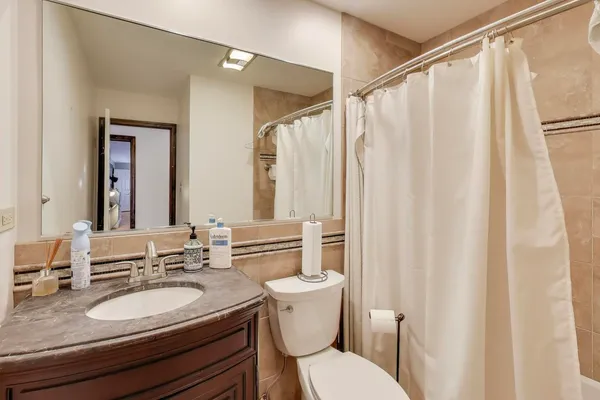 a bathroom with a granite countertop sink toilet and a mirror