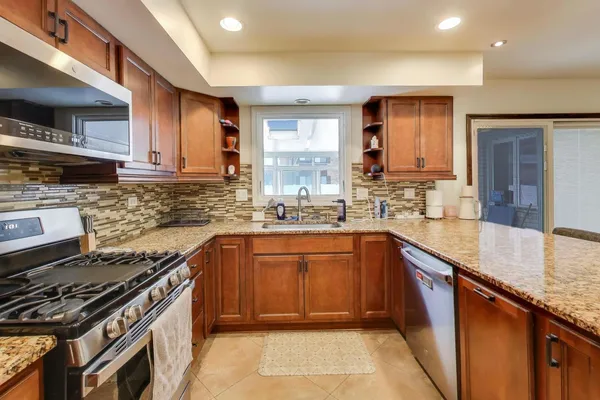 a kitchen with stainless steel appliances granite countertop a stove a sink and a microwave