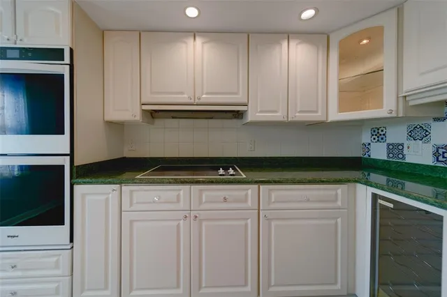 a kitchen with granite countertop white cabinets and stainless steel appliances