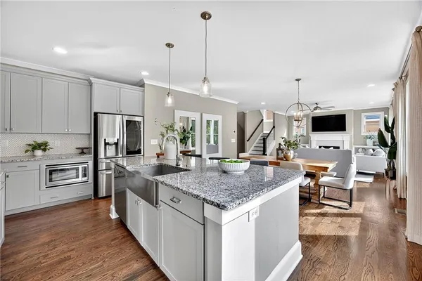 a kitchen with stainless steel appliances kitchen island granite countertop a stove top oven a sink dishwasher a dining table and chairs with wooden floor