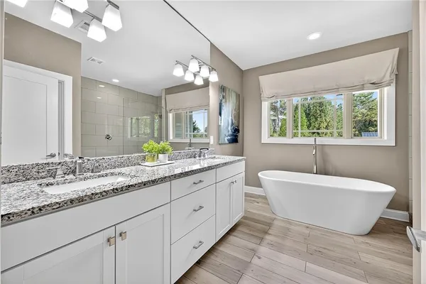 a spacious bathroom with a double vanity sink large mirror and a bathtub