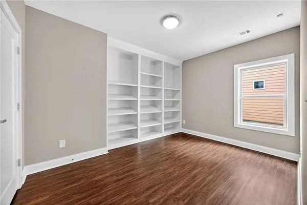 a view of an empty room with a window and wooden floor