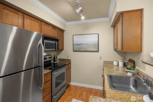 a kitchen with stainless steel appliances granite countertop a refrigerator a stove a sink a microwave oven with a dining table and chairs