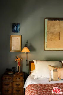 a bedroom with a bed and a lamp on dresser