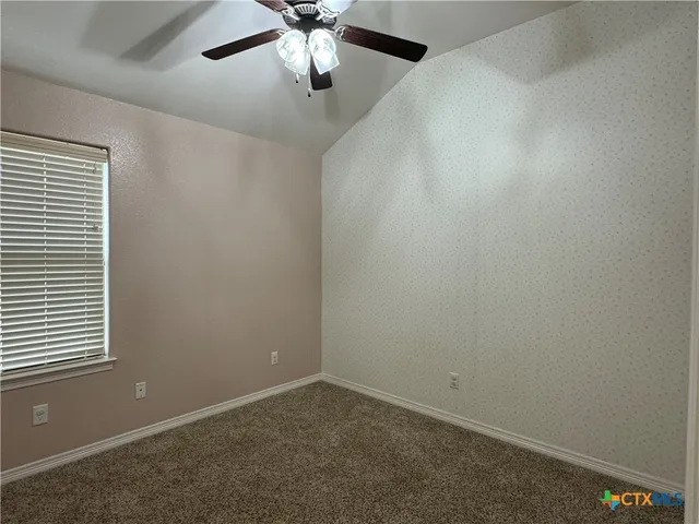en empty room with windows and ceiling fan