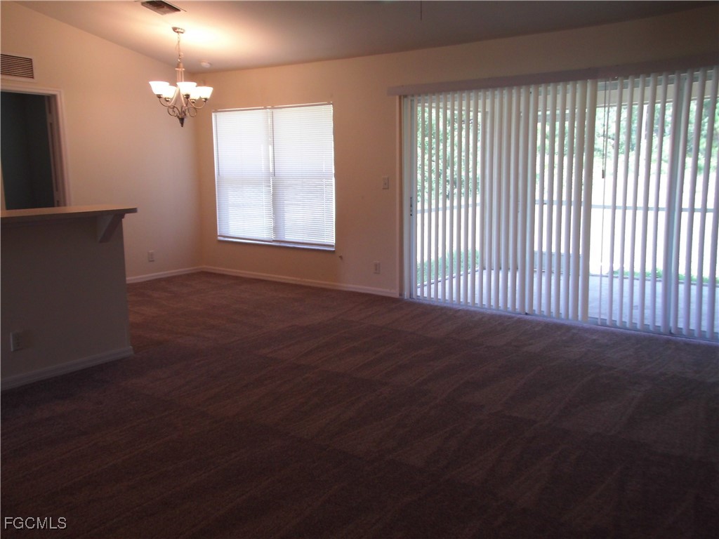 1117 Venetia Street Lehigh Acres, FL 33974 - Photo 2 of 10 an empty room with wooden floor and windows
