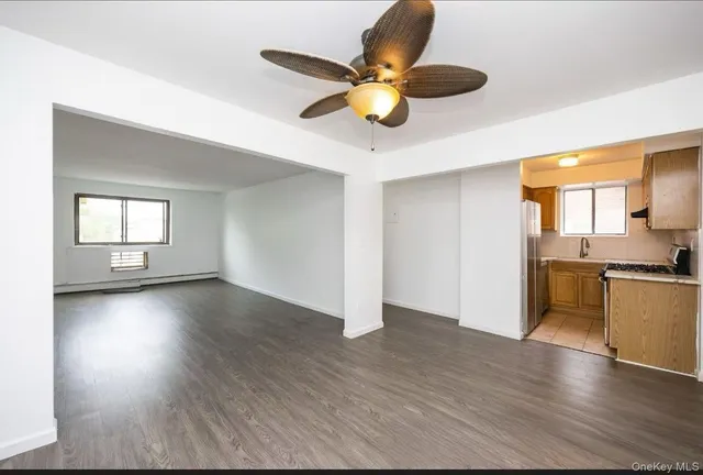 a view of an empty room with window and wooden floor