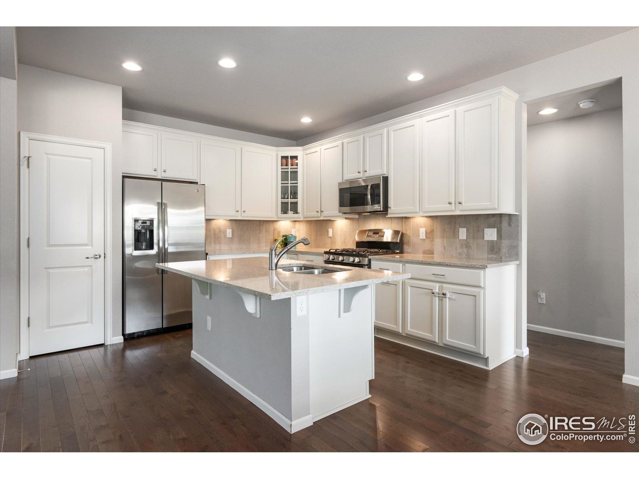 a kitchen with kitchen island granite countertop stainless steel appliances refrigerator sink and microwave