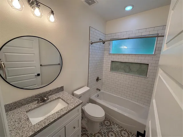 a bathroom with a granite countertop toilet sink and mirror
