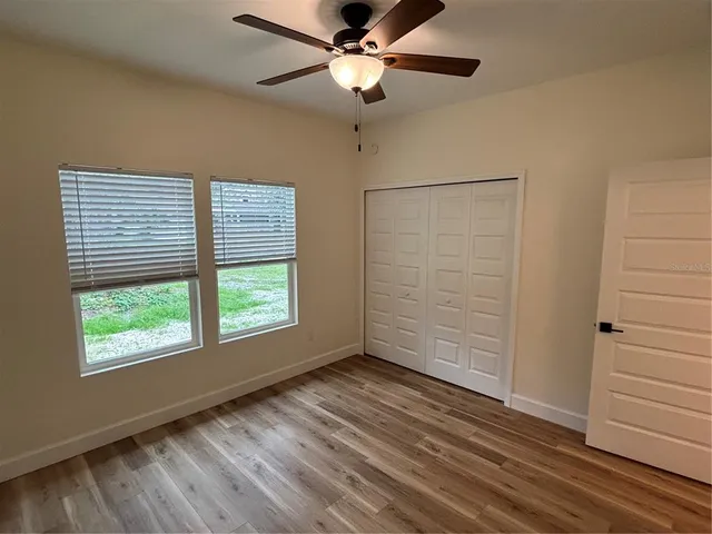 a view of an empty room with a window and wooden floor