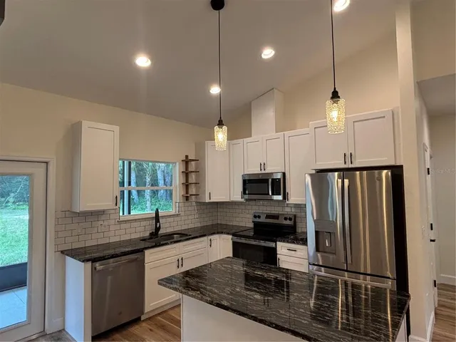 a kitchen with kitchen island granite countertop a stove a sink a refrigerator a center island a stove and a window