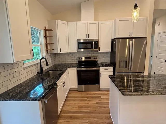 a kitchen with granite countertop a refrigerator stove and sink