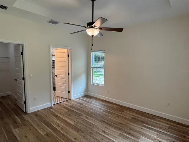 a view of a room with window ceiling fan and hardwood floor