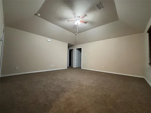 a view of an empty room and a chandelier fan