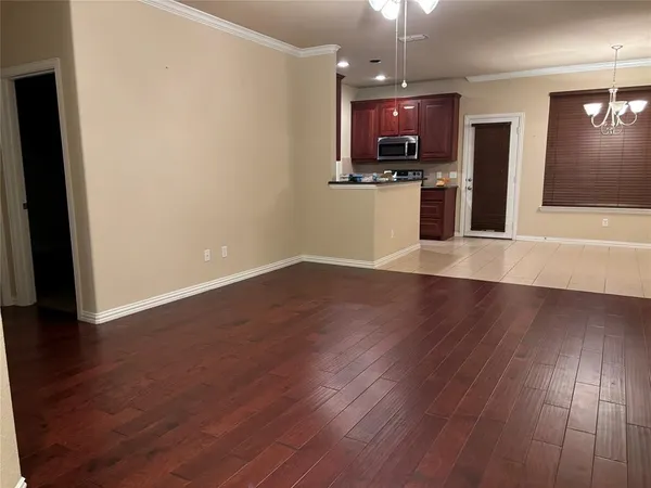 an empty room with wooden floor and a kitchen