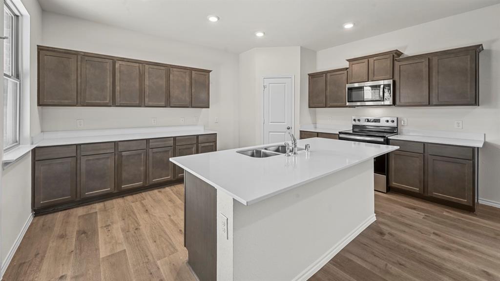 650 Glee Stem Road Lavon, TX 75166 - Photo 2 of 22 a kitchen with stainless steel appliances a sink a stove a microwave a center island and wooden floor