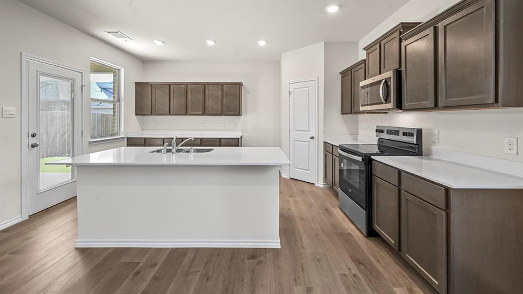 650 Glee Stem Road Lavon, TX 75166 - Photo 6 of 22 a kitchen with stainless steel appliances granite countertop a sink a stove top oven a refrigerator with wooden floors and cabinets