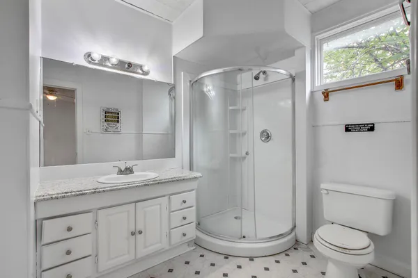 a bathroom with a granite countertop sink toilet a mirror a shower and a window