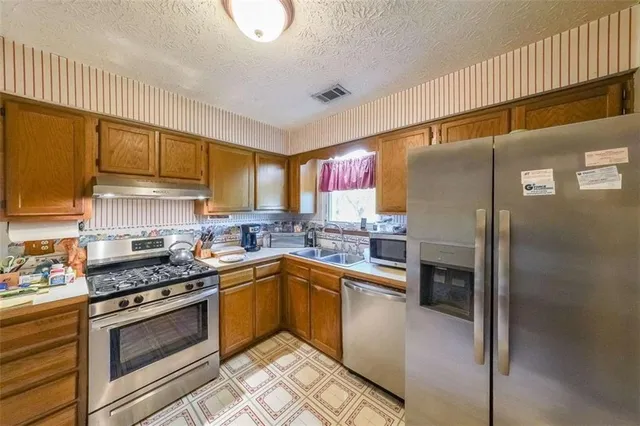 a kitchen with granite countertop a sink cabinets stainless steel appliances and a window
