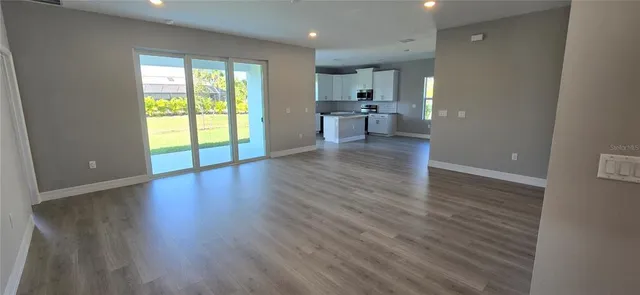 a view of empty room with wooden floor and a window